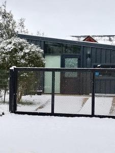 ein Zaun mit Schnee darauf vor einem Gebäude in der Unterkunft Cabaña Kunl Villa La Angostura moderna y accesible in Villa La Angostura