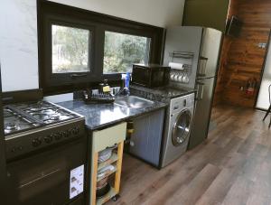 eine Küche mit Herd, Spüle und Kühlschrank in der Unterkunft Cabaña Kunl Villa La Angostura moderna y accesible in Villa La Angostura + 6 Fotos