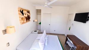 a white room with a bed and a tv at Hotel Riviera Inka Paracas in Paracas
