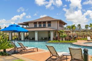 a house with a pool with chairs and an umbrella at Pili Mai 8K in Koloa