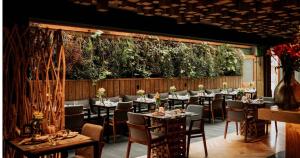 un restaurante con mesas y sillas y una pared con plantas en Wood Hotel Gramado, en Gramado