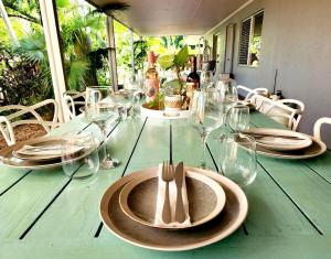 a green table with a plate and glasses on it at Clifton Beach Family Retreat with Pool in Clifton Beach