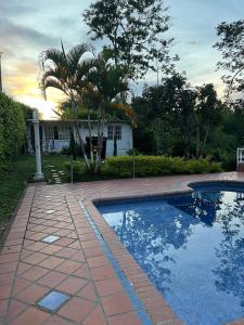 a swimming pool with a palm tree next to a house at Casa campestre con encanto in Armenia