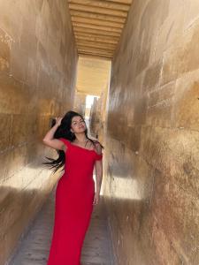 a woman in a red dress leaning against a wall at Pyramids Middle East stay&tours in Cairo