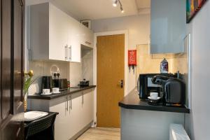 a kitchen with white cabinets and a black counter top at The Regent - Stylish Luxury Leicester Studio near City Centre! in Leicester