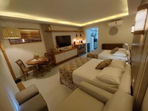 a hotel room with two beds and a couch at Búzios Beach Resort Apartamento Luxo Home Premium 2 in Búzios