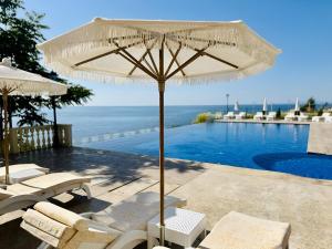 a white umbrella sitting next to a swimming pool at Santa Maria Luxury Suits in Ravda