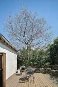 a table and chairs on a wooden deck with a tree at Jejuya Pyoseon in Seogwipo
