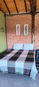 a bedroom with a bed in a brick wall at Chalé estrela do cruzeiro in São Thomé das Letras