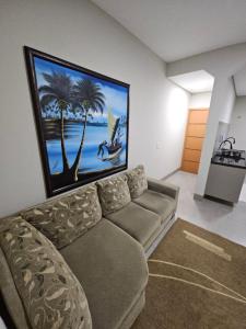 a living room with a couch and a painting on the wall at Flat Santa Teresa in Campo Verde
