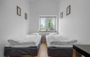 two beds in a room with a window at Four-Bedroom Holiday Home In Stroby in Strøby