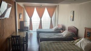 a hotel room with two beds and a table at Hotel Plaza Los Leones in Curanilahue