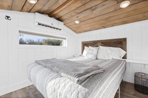 a bed in a white room with a window at Tiny Home | Lewis Ranch 1 in Lindsay