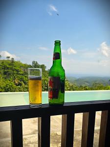 eine Flasche Bier sitzt auf einem Geländer mit einem Glas in der Unterkunft Dudu Cottage Nusa Penida in Nusa Penida