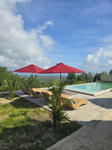 einen Pool mit Sonnenschirmen und Stühlen neben einem Pool in der Unterkunft Dudu Cottage Nusa Penida in Nusa Penida