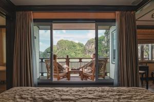 a man sitting in a chair on the balcony of a bedroom at Heritage Line Ginger Cruise - Halong Bay & Lan Ha Bay in Ha Long