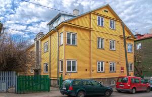 a yellow house with two cars parked in front of it at Patarei Apartment in Tallinn