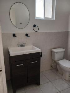 Un baño con lavabo, inodoro y espejo. en Kasa koko, en Cancún 21 fotos más