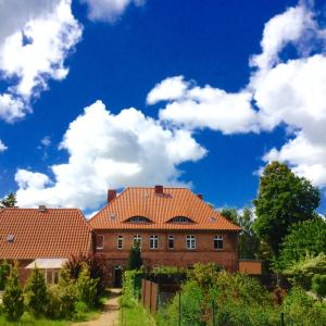 Lischow的住宿－Haus 2 Linden，两座房子,有红色屋顶,有蓝色的天空,有云
