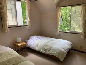 a bedroom with two beds and two windows at ペンションエバーグリーン in Fujimi