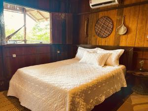 a bedroom with a bed with white sheets and a window at Ponta Poranga Jungle Lodge in Manaus