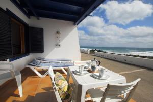 una mesa blanca y sillas en un balcón con vistas al océano en Casita Lanzaocean view, en Punta Mujeres