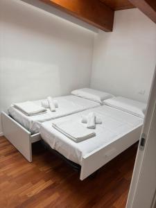 two beds in a room with white walls and wooden floors at aMare27 in Citta' Sant'Angelo
