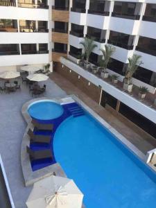 a large swimming pool in a building with umbrellas at Gold Flat by Nomar Hospedagem 610 in João Pessoa