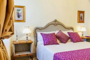 a bedroom with a white bed with purple pillows at Private Villa Among Pine Trees And Lavender in Marina di Grosseto +13 photos