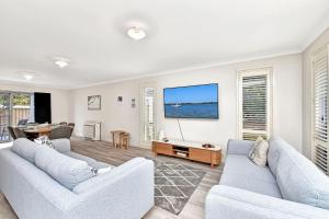 a living room with two couches and a tv at Seaspray Haven, 10 Seaspray Ave - air con, complex pool, Wi-Fi, Linen in Nelson Bay