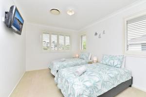a bedroom with two beds and a flat screen tv at Seaspray Haven, 10 Seaspray Ave - air con, complex pool, Wi-Fi, Linen in Nelson Bay +20 photos