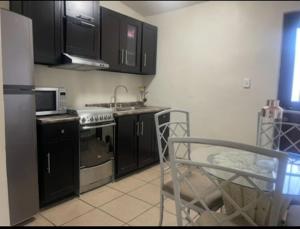 a kitchen with black cabinets and a stove top oven at Villas Casa 4 Camas de 1 planta in Hermosillo