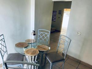 a glass table with four chairs and a bottle on it at Villas Casa 4 Camas de 1 planta in Hermosillo