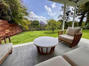 a patio with a table and a couch and a chair at The Eco Shed - Private Riverfront Getaway - Close to Town - Pet Friendly in Bellingen