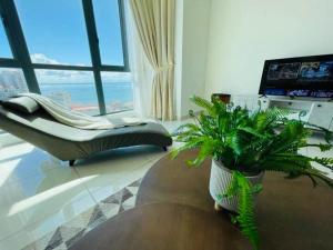 ein Wohnzimmer mit einer Couch und einer Pflanze in der Unterkunft Deluxe Seaview Suite Tripe Bed with bath tub 25 in Tanjong Tokong