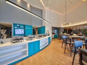 a kitchen with blue cabinets and tables and chairs at Magnotel Ningbo Tianyi Plaza Railway Station in Ningbo