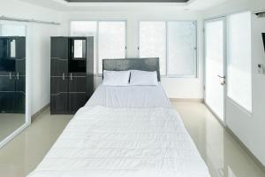 a bedroom with a large bed with white sheets at RedDoorz near Politeknik Pariwisata Nusa Dua Bali in Nusa Dua +16 photos