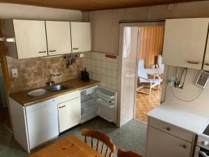 a kitchen with white cabinets and a sink and a table at Gramimmo - Appartement La Cascade in Salvan