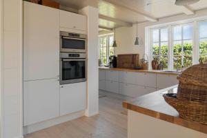 a kitchen with white cabinets and a counter at Modern Holiday Home Where Indoor And Outdoor Merge in Hals +27 photos