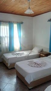 2 camas en una habitación con cortinas azules en Mila Pansiyon, en Cıralı