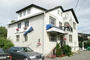 a white house with a car parked in front of it at White Villa in Tallinn