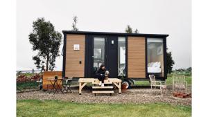 a woman sitting at a picnic table in front of a tiny house at Maluridae Creek Views by Tiny Away in Lawrence