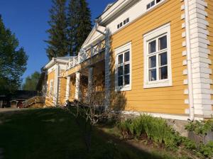 une maison jaune avec des fenêtres blanches et une cour dans l'établissement Tiittalan Kartano, à Sulkava