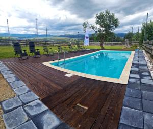 a pool with a wooden deck and chairs around it at Prosilva House Banffy 2 in Topliţa