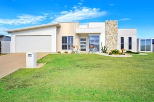 a white house with a garage on a lawn at Cinema Pool Pets 4b2b Bargara Headlands in Pemberton