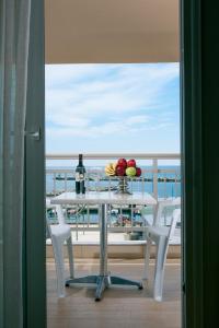 a table with a bottle of wine and fruit on a balcony at Protea's Seacret Sea View Studios in Paralia Katerinis