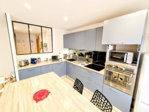 a kitchen with a wooden table and a kitchen with white cabinets at Une halte, Proche Notre-Dame in Rodez