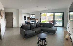 a living room with a couch and a table at Charmante maison récente avec PISCINE CHAUFFEE proche Nîmes in Beaucaire