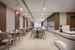 ein Esszimmer mit Tischen und Stühlen und eine Küche in der Unterkunft Ramada Encore by Wyndham Jinan Shanghe in Shang-ho-hsien