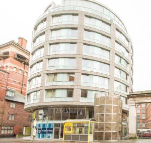 a yellow bus parked in front of a tall building at PREMIER SUITES Liverpool in Liverpool